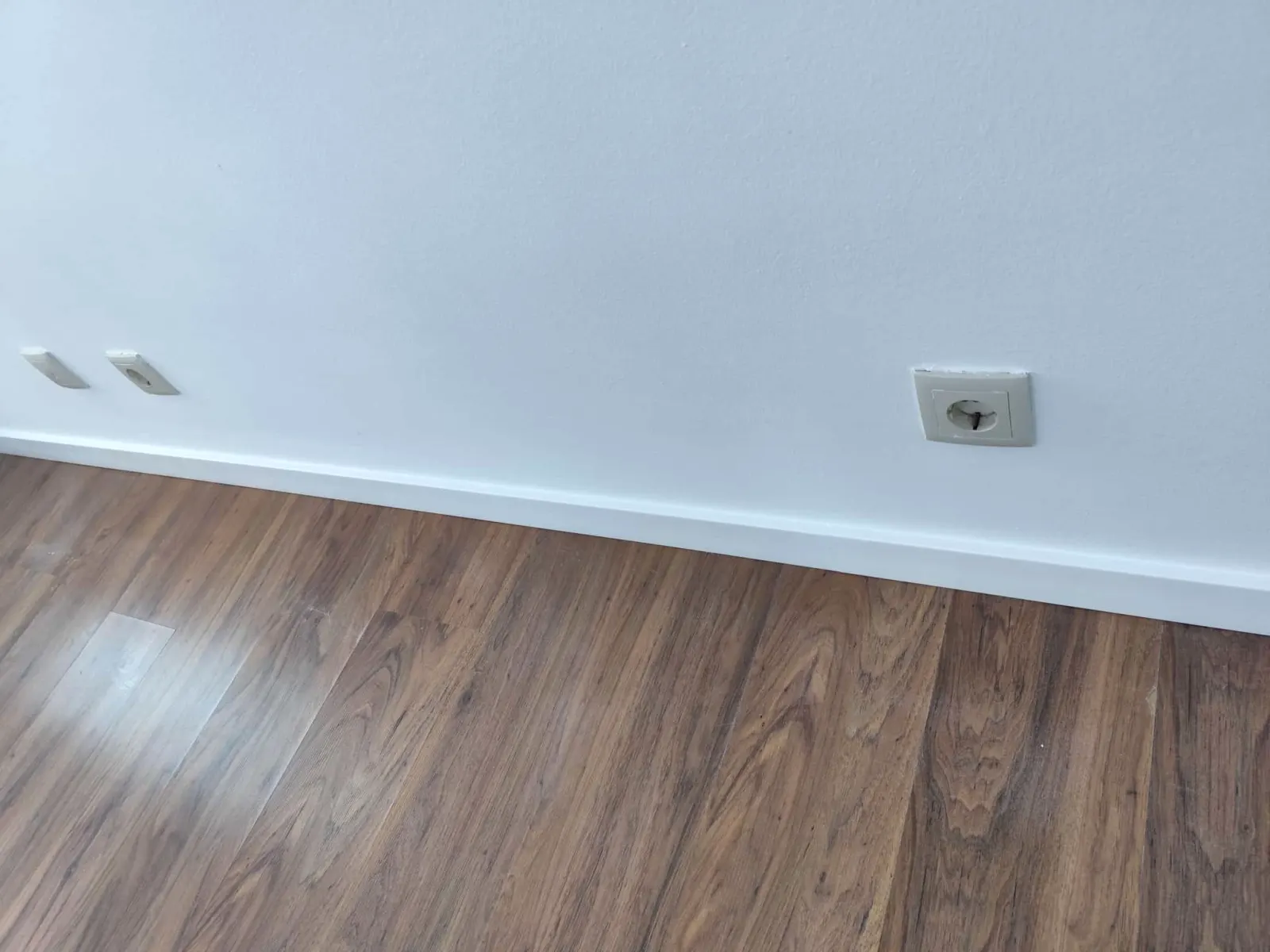 Pormenor de rodapé branco e pavimento flutuante