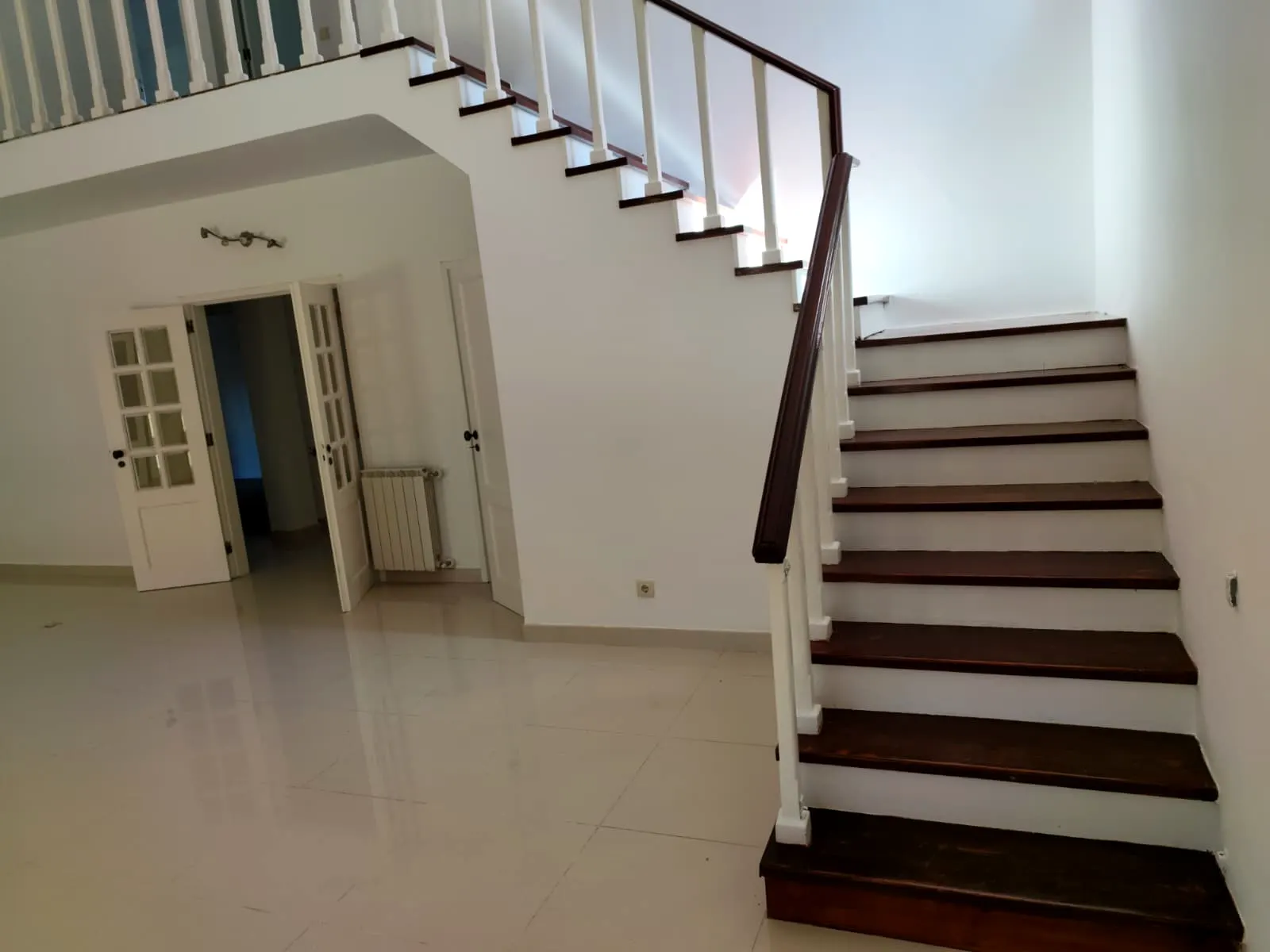 Escada interior com degraus em madeira e paredes brancas