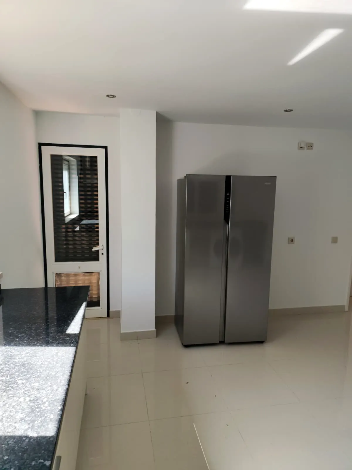 Cozinha com frigorífico e paredes brancas renovadas