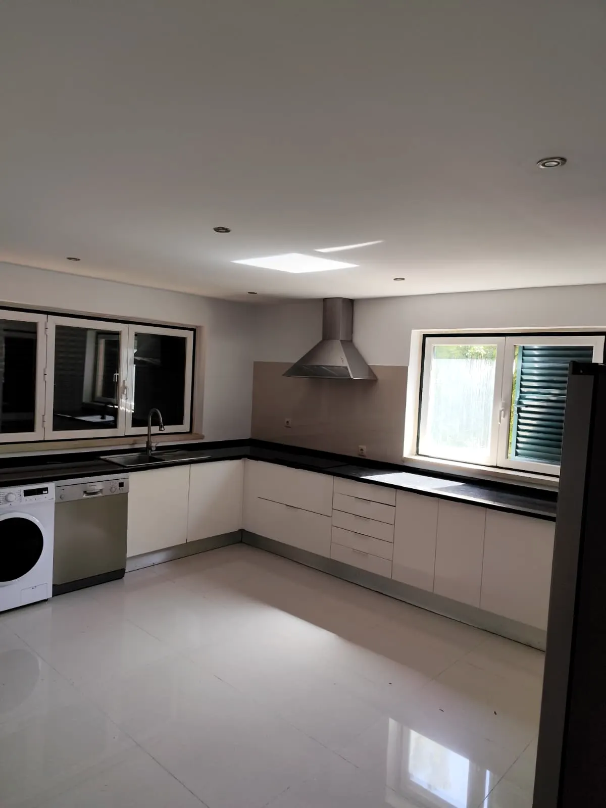 Cozinha branca com bancada escura e iluminação natural